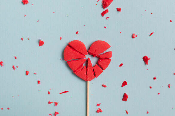 Valentine day concept with broken red lollipop heart on pastel blue background top view. Flat lay greeting card concept.