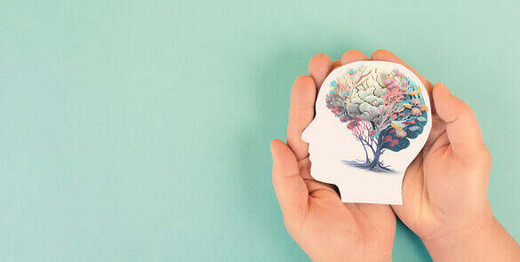 Hands holding paper head, human brain with flowers, self care and mental health concept, positive thinking, creative mind